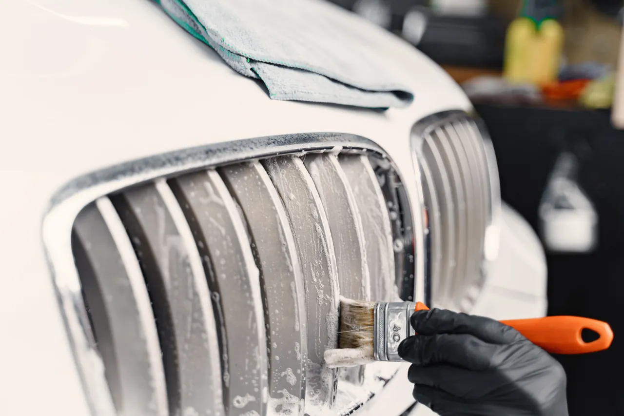 A detail brush cleaning a vehicle grille